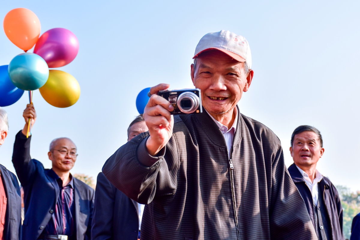 14 队列拿着相机拍照的老人【学通社记者 于君摄】